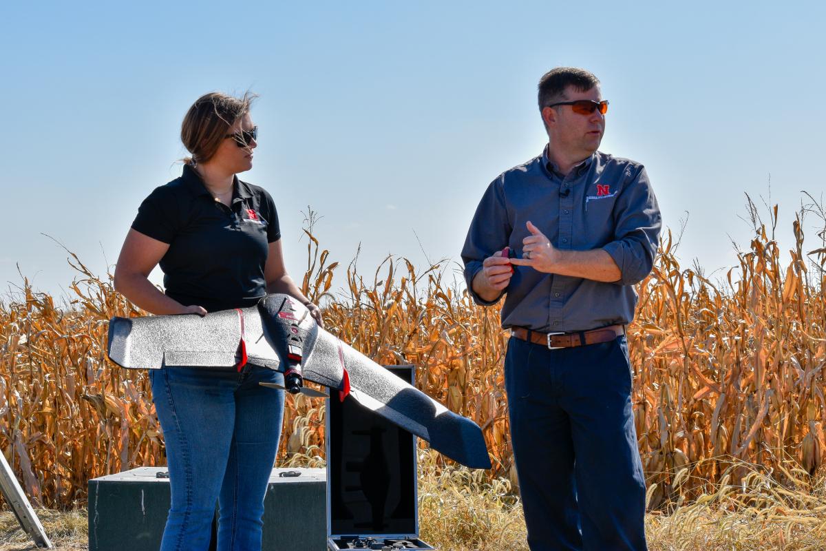 Two educators demonstrate a agricultural drone in the field.