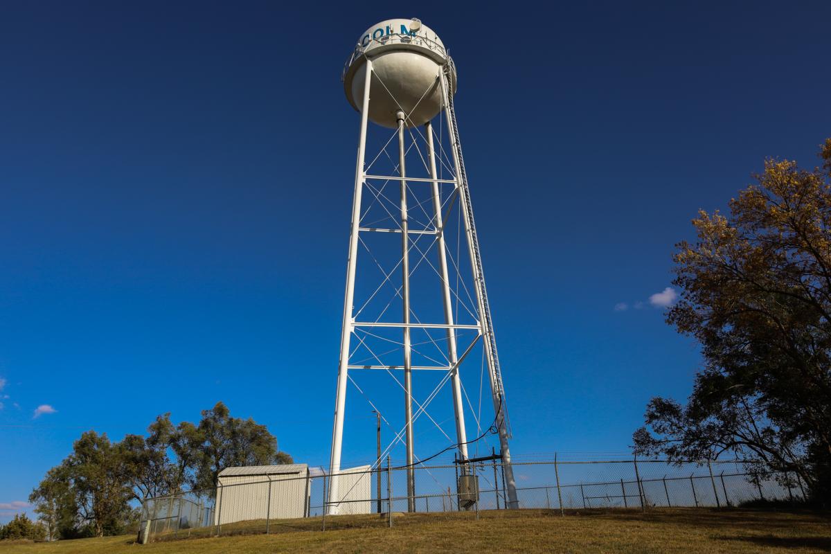 A tall water tower standing against a dark blue sky.