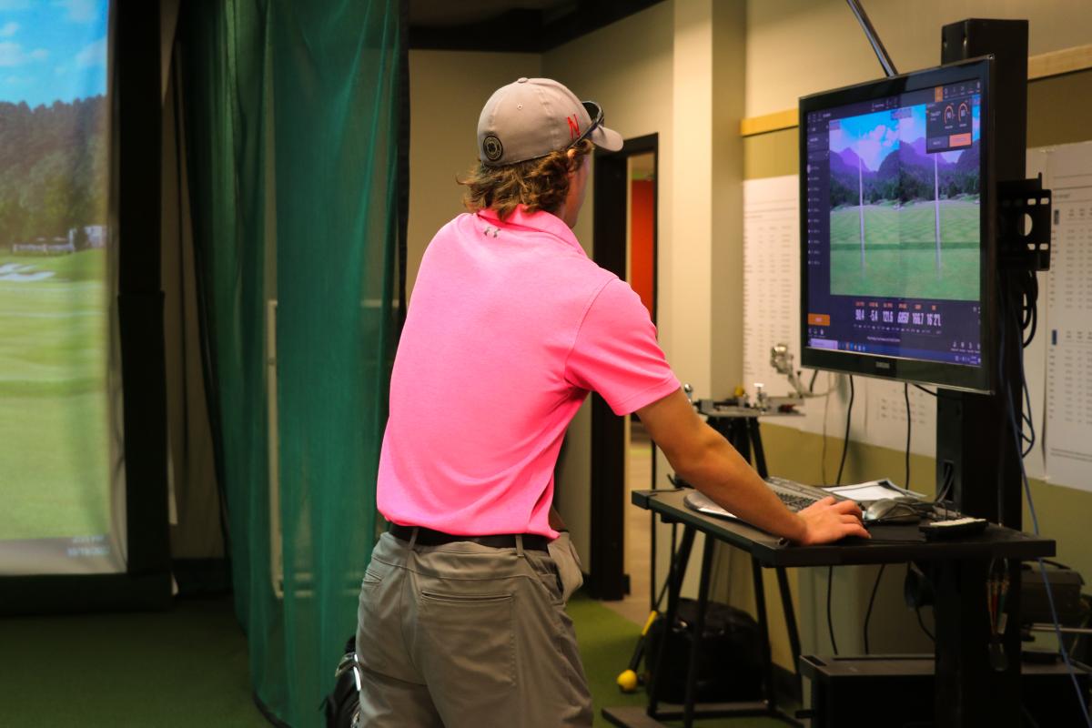 A person standing in front of a golf simulator.