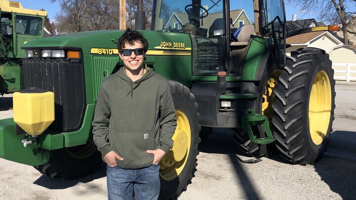 Landan Cuba posing in front of a tractor.