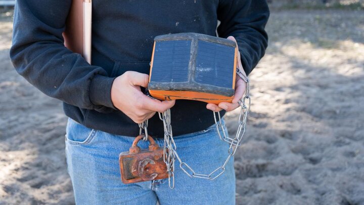 Person holds a cattle tracking collar.