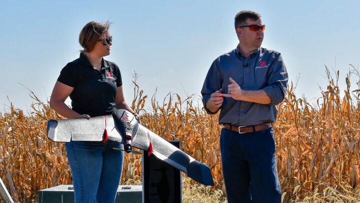 Two educators demonstrate a agricultural drone in the field.