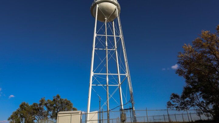 A tall water tower standing against a dark blue sky.