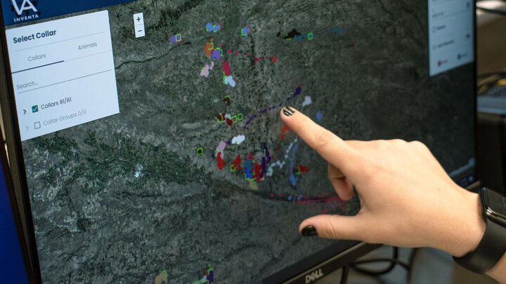 A hand pointing to a computer screen that is displaying the location of radio-collared pronghorn.