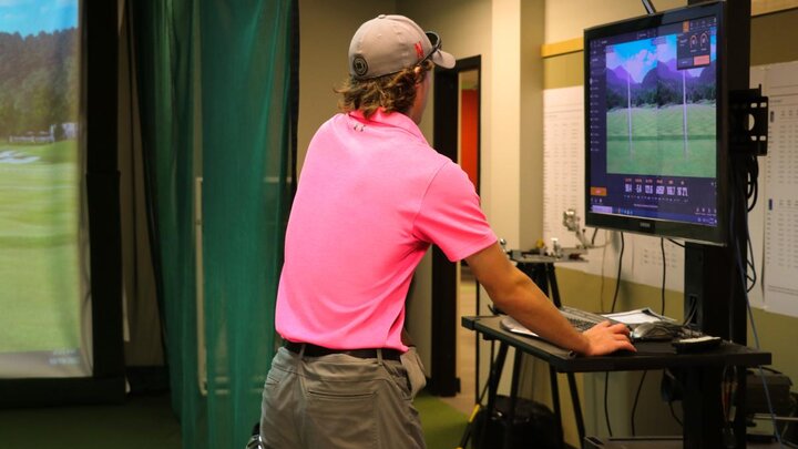 A person standing in front of a golf simulator.